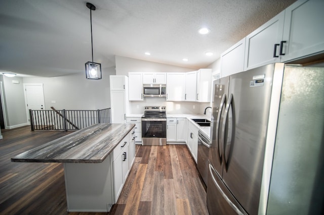 kitchen with white cabinets, a center island, stainless steel appliances, sink, and vaulted ceiling