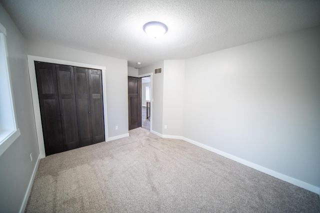 unfurnished bedroom featuring carpet floors, a textured ceiling, and a closet