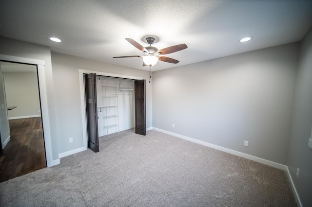 unfurnished bedroom featuring ceiling fan, a closet, a textured ceiling, and carpet flooring