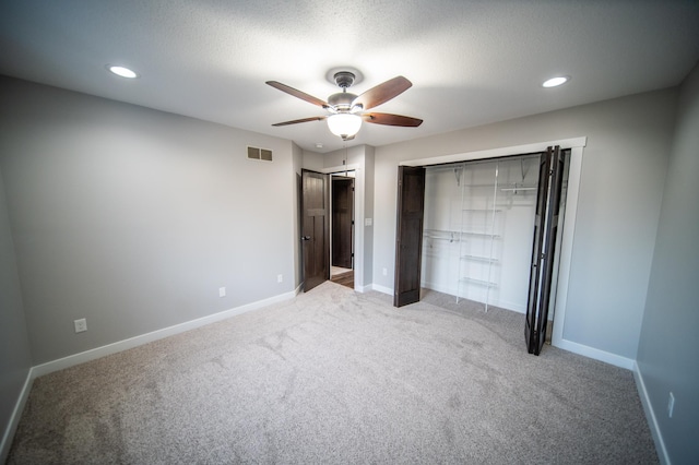 unfurnished bedroom with ceiling fan, light colored carpet, a textured ceiling, and a closet