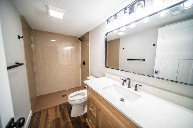 bathroom featuring toilet, vanity, hardwood / wood-style floors, a shower, and a textured ceiling