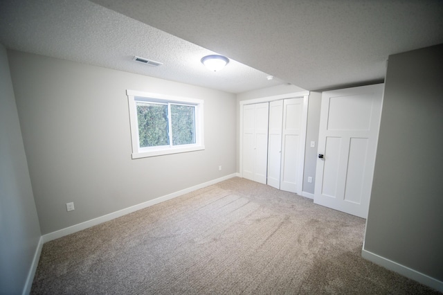 unfurnished bedroom with a textured ceiling, a closet, and carpet floors