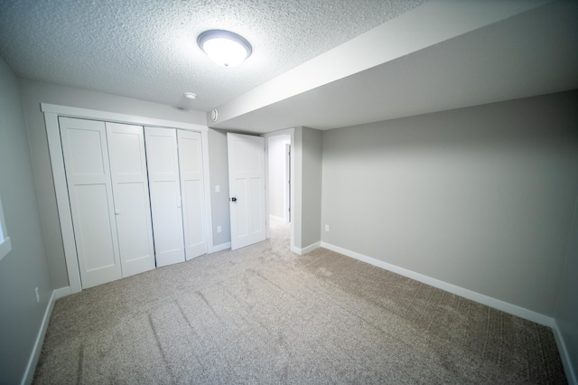 unfurnished bedroom featuring a textured ceiling, a closet, and carpet floors