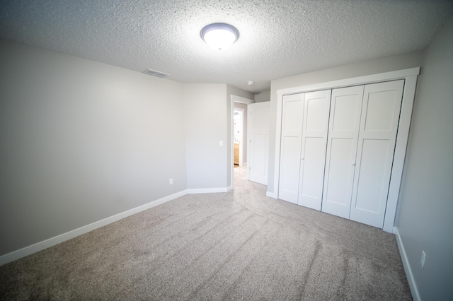 unfurnished bedroom featuring carpet floors, a textured ceiling, and a closet