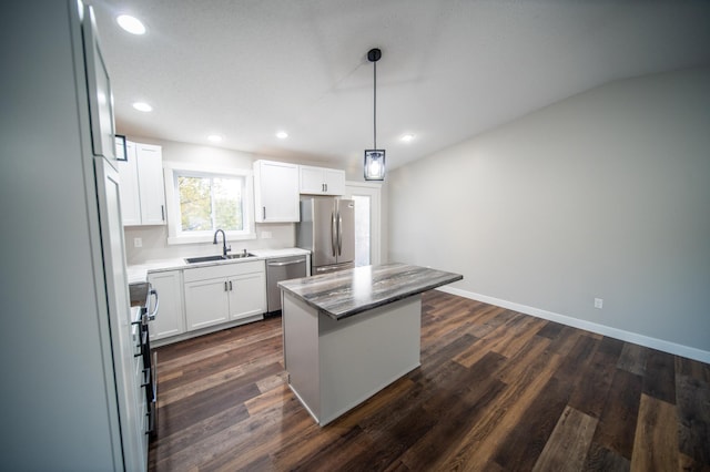 kitchen with white cabinets, a kitchen island, decorative light fixtures, stainless steel appliances, and sink