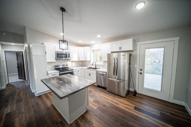 kitchen with vaulted ceiling, pendant lighting, a kitchen island, sink, and stainless steel appliances