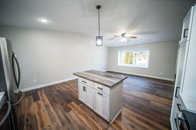 kitchen with ceiling fan, dark hardwood / wood-style flooring, stainless steel refrigerator, pendant lighting, and white cabinets