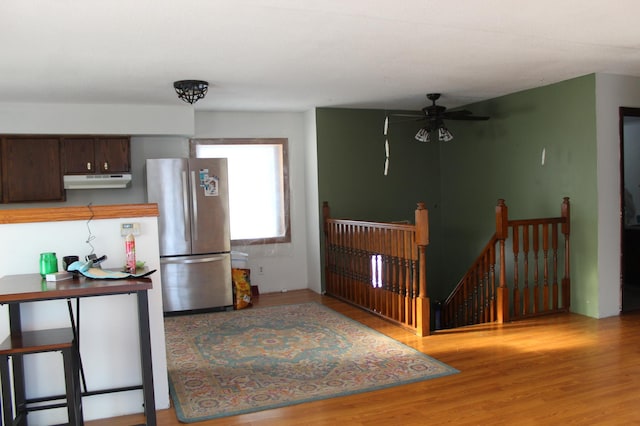 kitchen featuring ceiling fan, wood-type flooring, stainless steel fridge, and dark brown cabinetry