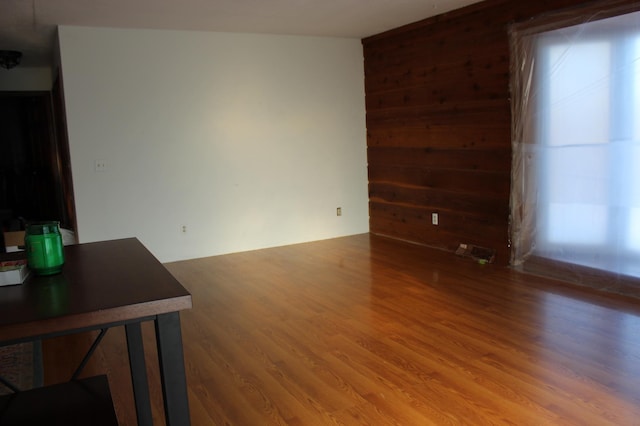 unfurnished living room with wood-type flooring and wood walls