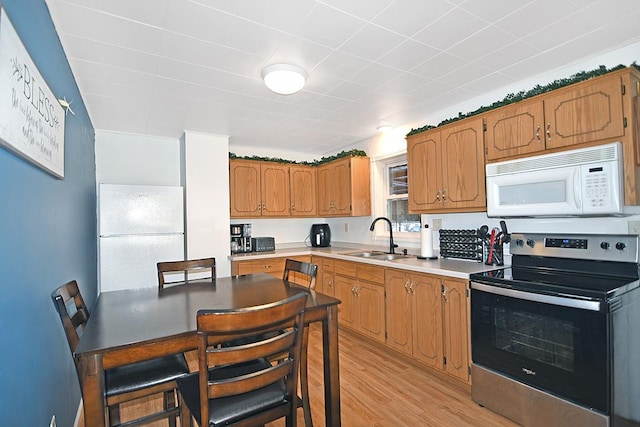 kitchen featuring sink, white appliances, and light hardwood / wood-style floors