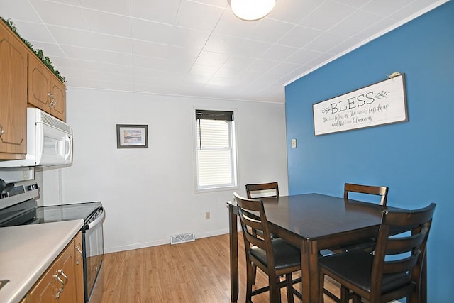 dining space with light wood-type flooring and crown molding