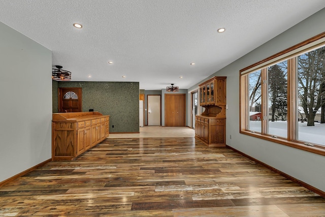 unfurnished living room with a textured ceiling and dark hardwood / wood-style flooring