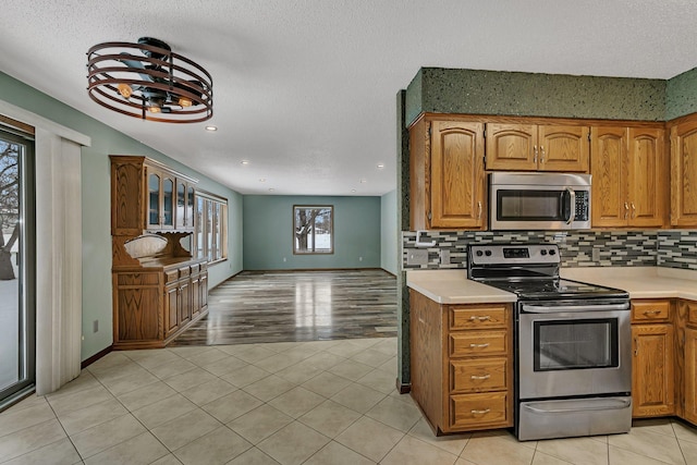 kitchen featuring light tile patterned flooring, stainless steel appliances, a textured ceiling, and backsplash