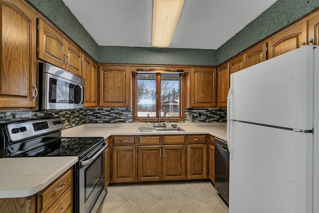 kitchen featuring decorative backsplash, sink, stainless steel appliances, a textured ceiling, and light tile patterned floors