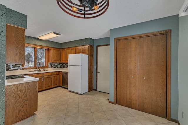 kitchen with backsplash, a textured ceiling, white refrigerator, stainless steel dishwasher, and sink