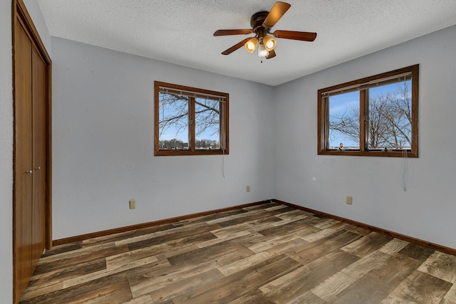 unfurnished bedroom with ceiling fan, dark hardwood / wood-style floors, and a textured ceiling