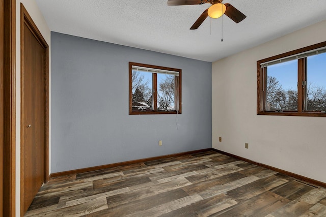 unfurnished bedroom featuring a textured ceiling, ceiling fan, dark hardwood / wood-style flooring, and multiple windows