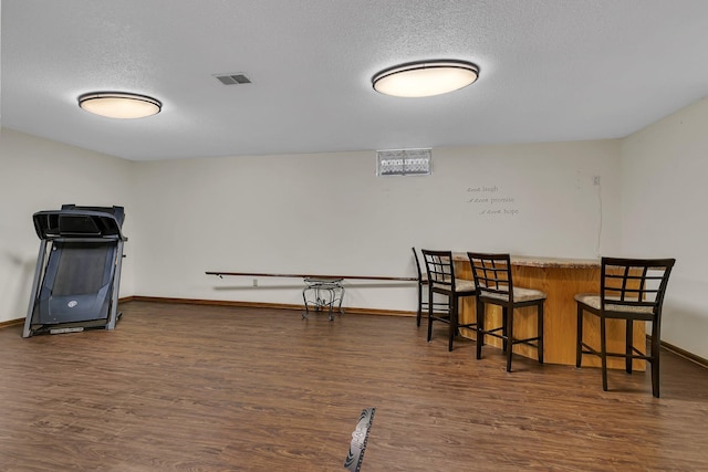 dining room featuring a textured ceiling, indoor bar, and dark hardwood / wood-style floors