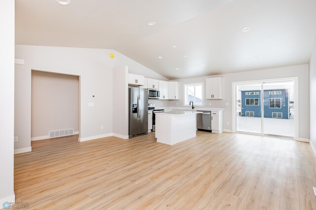 kitchen with vaulted ceiling, a center island, light wood-type flooring, white cabinets, and appliances with stainless steel finishes