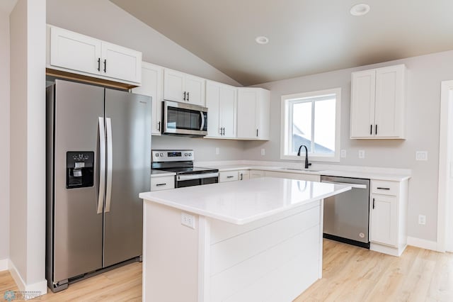 kitchen featuring vaulted ceiling, a center island, white cabinets, appliances with stainless steel finishes, and sink