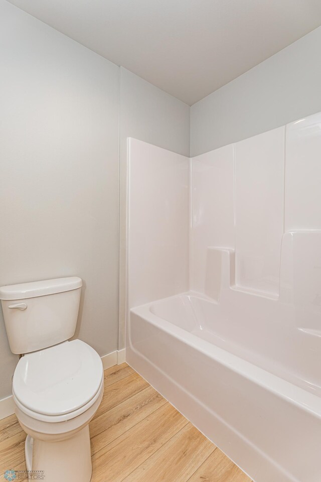 bathroom with toilet, tub / shower combination, and wood-type flooring