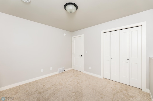 unfurnished bedroom with light colored carpet and a closet