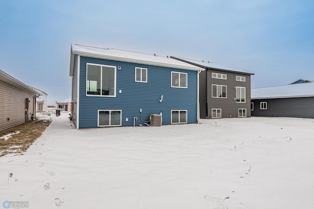 snow covered rear of property featuring central air condition unit