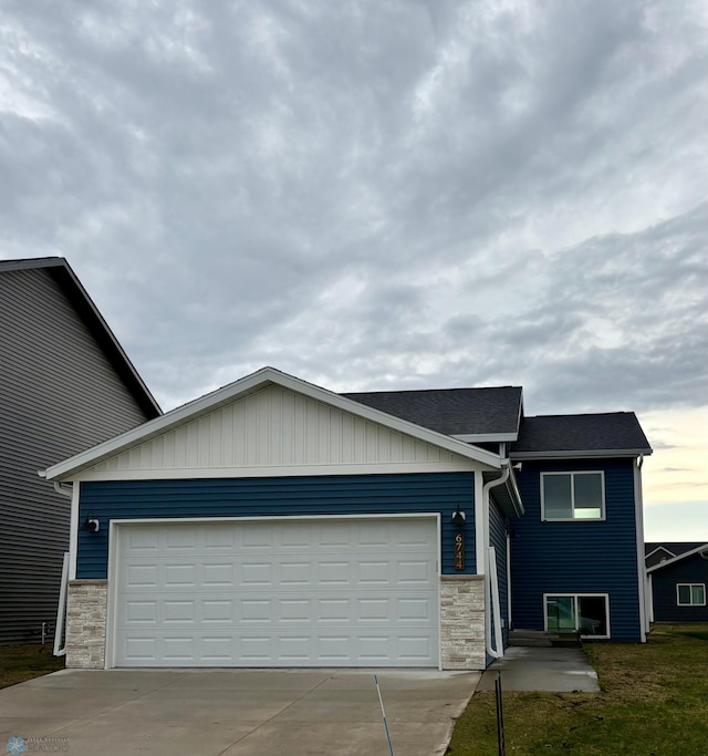 6744 66th Ave S, Horace, ND 58047 - view of front facade with stone siding, concrete driveway, an attached garage, and board and batten siding