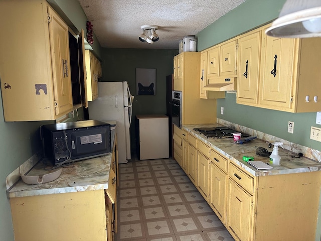 kitchen with refrigerator, a textured ceiling, gas cooktop, range hood, and white fridge