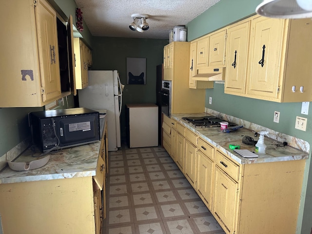 kitchen featuring white fridge, a textured ceiling, and stainless steel gas cooktop