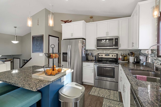 kitchen with white cabinetry, stainless steel appliances, lofted ceiling, and backsplash