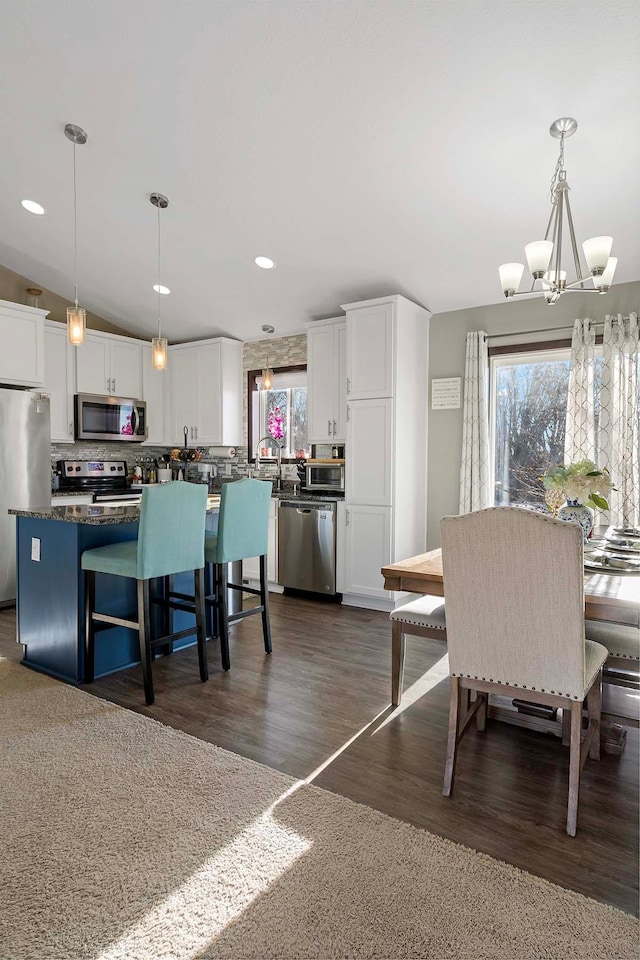 dining space featuring dark hardwood / wood-style floors, an inviting chandelier, and vaulted ceiling