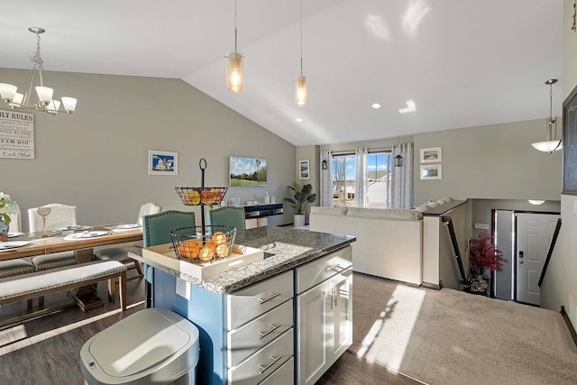 kitchen featuring light stone countertops, pendant lighting, a center island, and vaulted ceiling