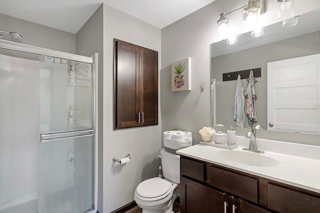 bathroom featuring toilet, vanity, and a shower with door