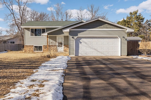 view of front of house with driveway, an attached garage, fence, and brick siding