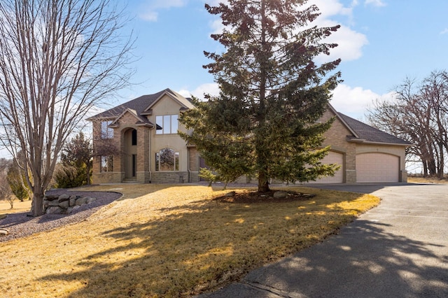 view of front of property featuring aphalt driveway, stone siding, an attached garage, and stucco siding