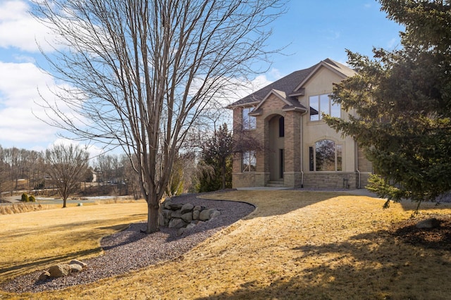 view of front of property with stucco siding, stone siding, and a front yard