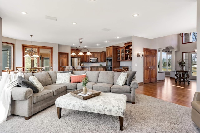 living room featuring a notable chandelier, recessed lighting, and light wood-type flooring