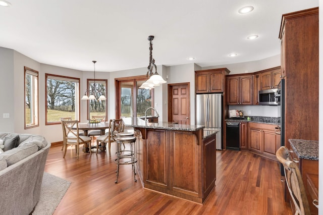 kitchen featuring a breakfast bar, dark wood finished floors, recessed lighting, appliances with stainless steel finishes, and open floor plan