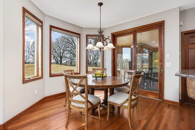 dining area with light wood-style flooring, a notable chandelier, and baseboards