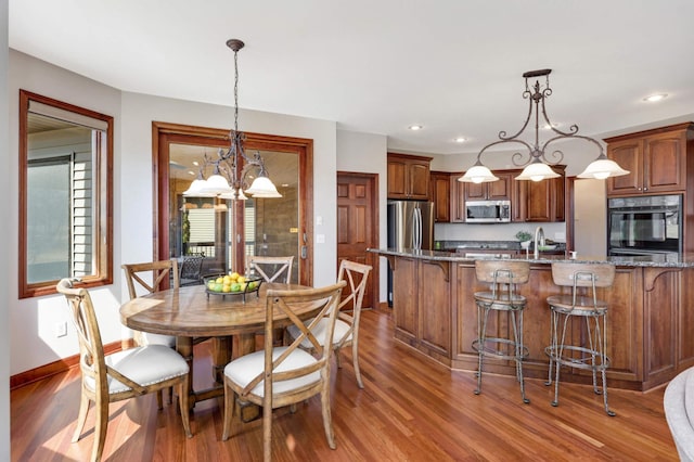 dining room with recessed lighting, baseboards, an inviting chandelier, and wood finished floors