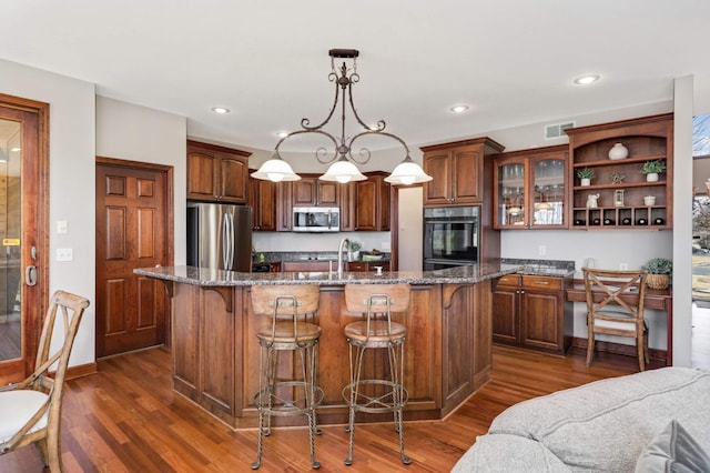 kitchen featuring open shelves, dark wood-style flooring, stainless steel appliances, glass insert cabinets, and a kitchen breakfast bar