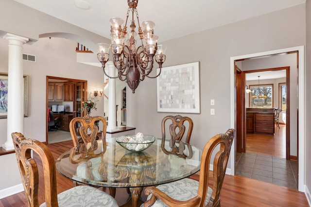 dining area with visible vents, wood finished floors, arched walkways, an inviting chandelier, and baseboards