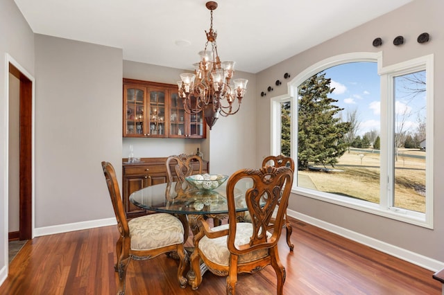 dining space featuring a chandelier, baseboards, and dark wood-style floors