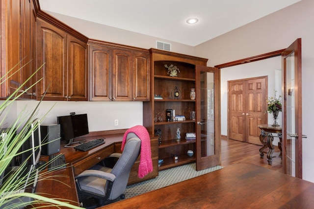 office with wood finished floors, visible vents, and built in desk