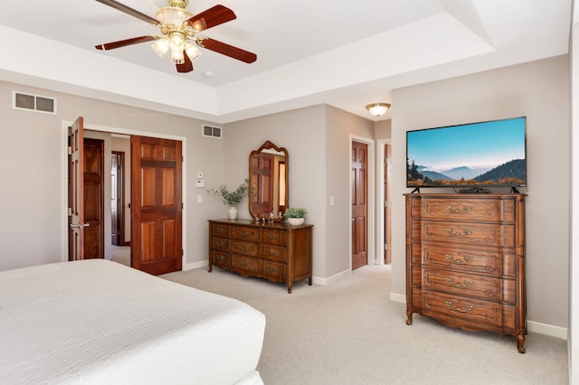 bedroom featuring light carpet, visible vents, baseboards, and a tray ceiling