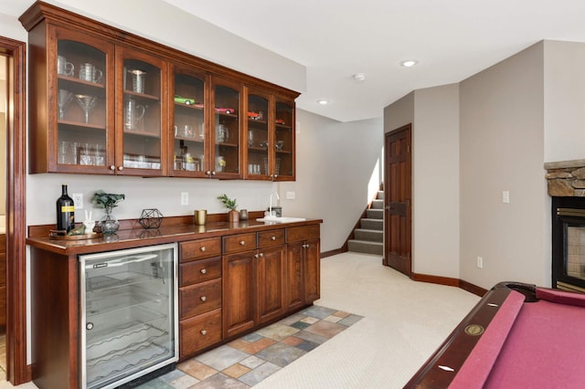 bar featuring beverage cooler, baseboards, a sink, stairs, and a bar