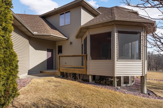 view of front of home with a front yard, a sunroom, and a shingled roof