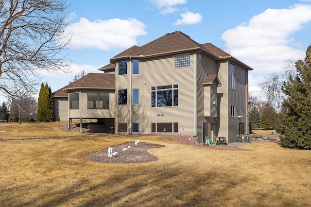 back of property featuring a yard, central AC unit, and roof with shingles