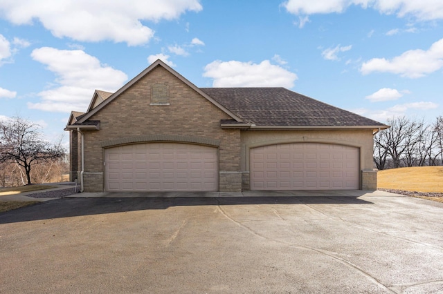 view of front of home featuring brick siding, driveway, and roof with shingles